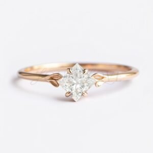 Princess cut moissanite ring set diagonally with four claw prongs and two gold leaves on the band.