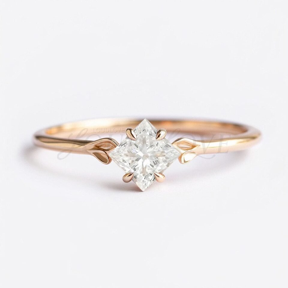 Princess cut moissanite ring set diagonally with four claw prongs and two gold leaves on the band.