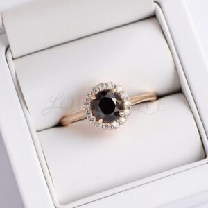 Round black diamond ring with white halo set in rose gold, displayed in a ring box.