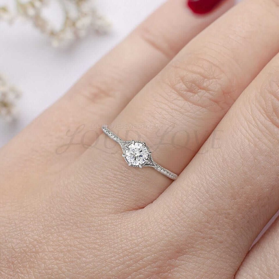 White gold ring with round moissanite, milgrain accents, and unique band texture.