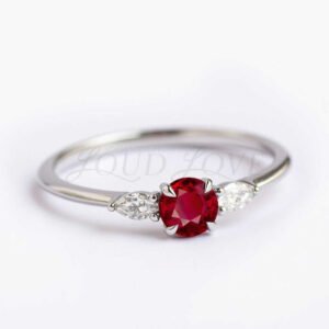 Side view of a three-stone ruby ring with a round center and marquise moissanite side stones.