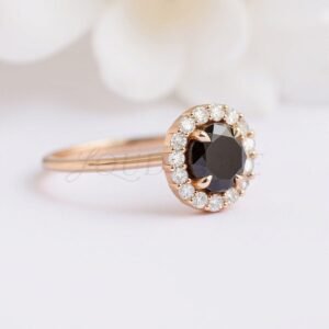 Side view of a black diamond ring with halo in a rose gold setting.