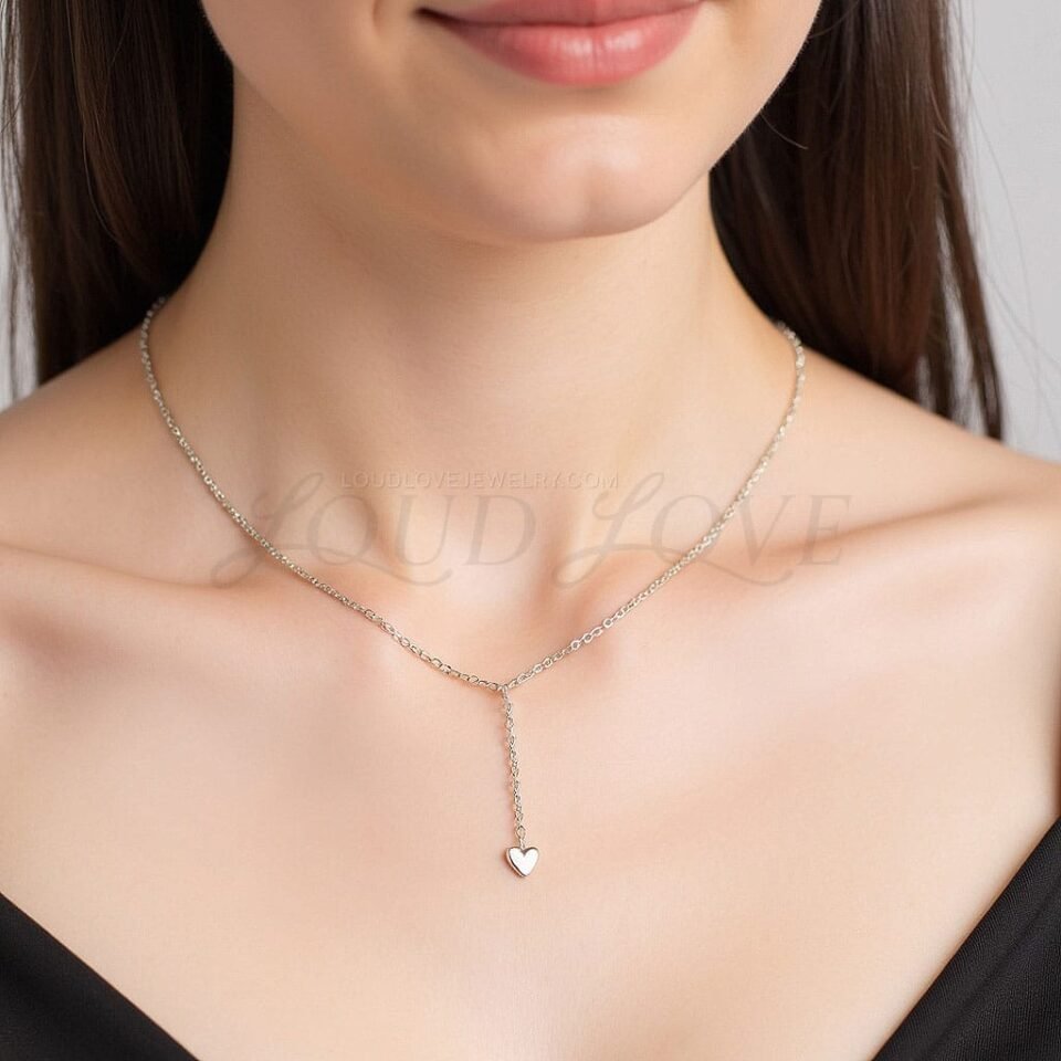 Fine chain drop necklace with a petite heart detail, worn to accent the collarbone gracefully.