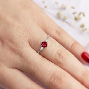 Round ruby flanked by white marquise stones in a thin silver setting, elegant and simple.
