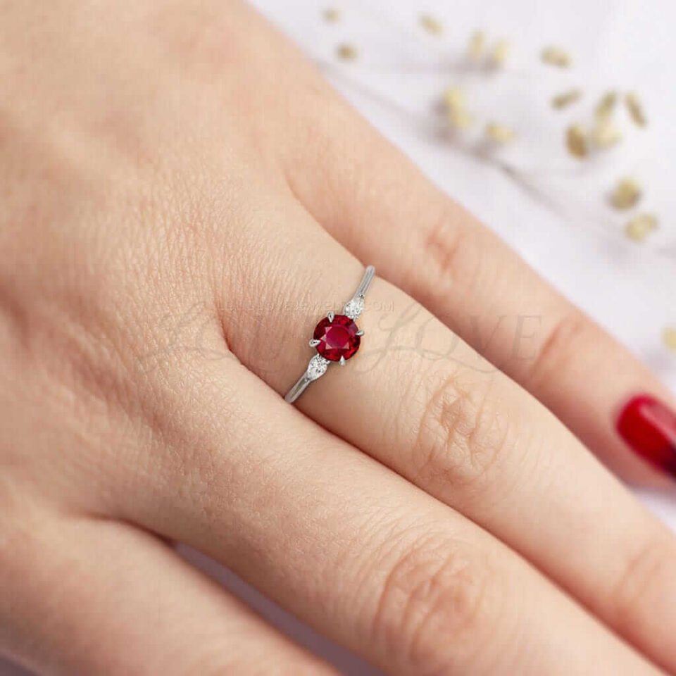 Round ruby flanked by white marquise stones in a thin silver setting, elegant and simple.