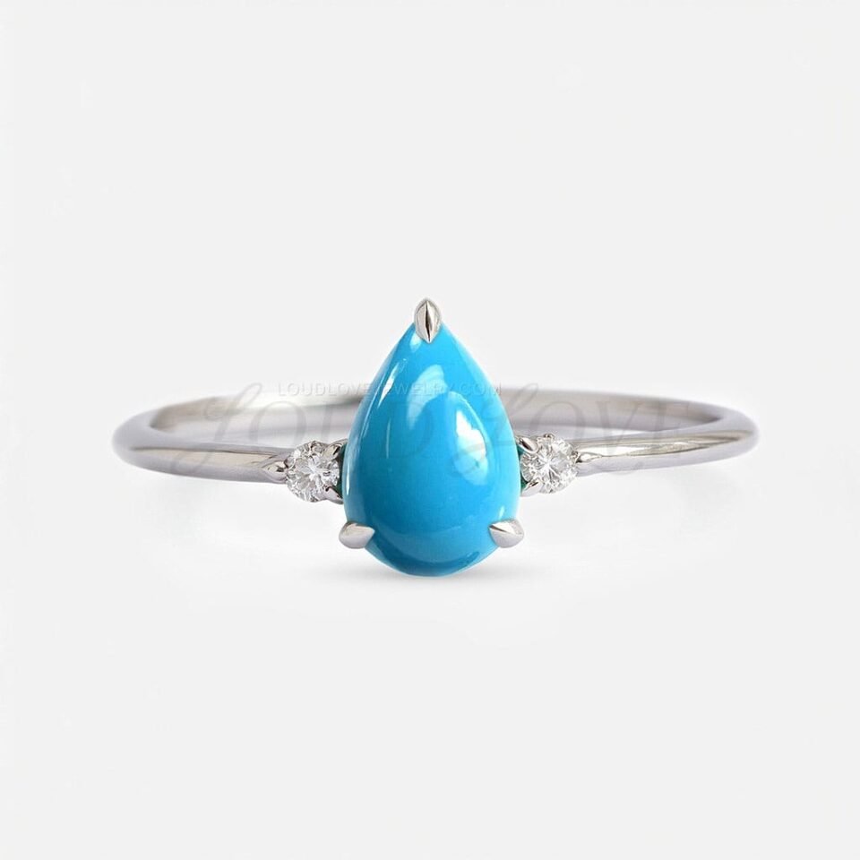 Sterling silver ring with pear-shaped turquoise cabochon and two round white accent stones.