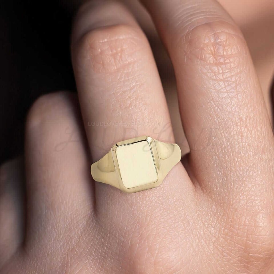Gold signet ring with emerald cut shape worn as a classic men’s wedding or fashion ring.