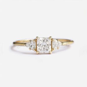 Princess cut moissanite ring with triangle-cut side stones and yellow gold band, front view.
