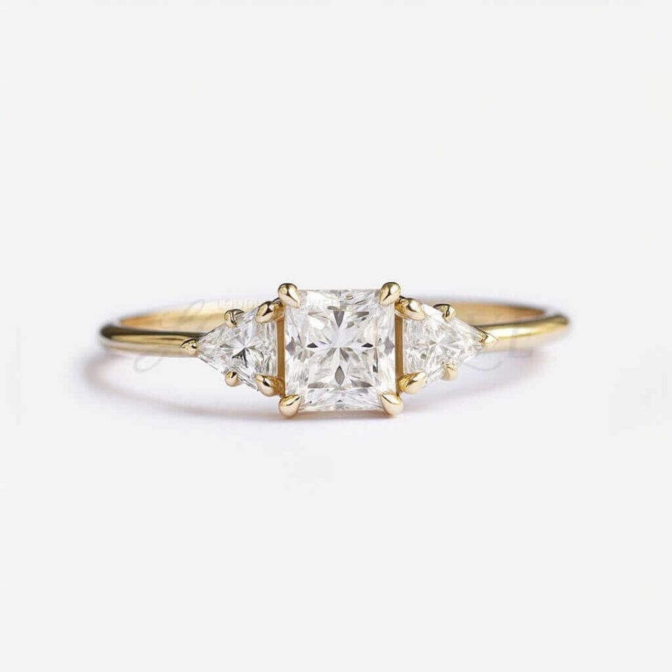 Princess cut moissanite ring with triangle-cut side stones and yellow gold band, front view.