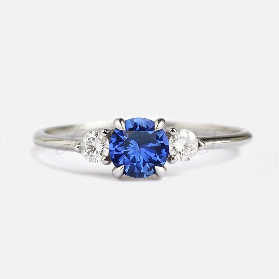 Round lab sapphire with one white side stone on each side in a classic three-stone design.