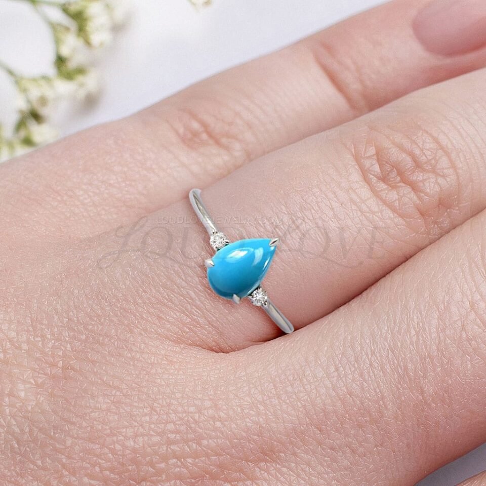 Pear cabochon turquoise with white side stones in sterling silver, worn to show three-stone layout.