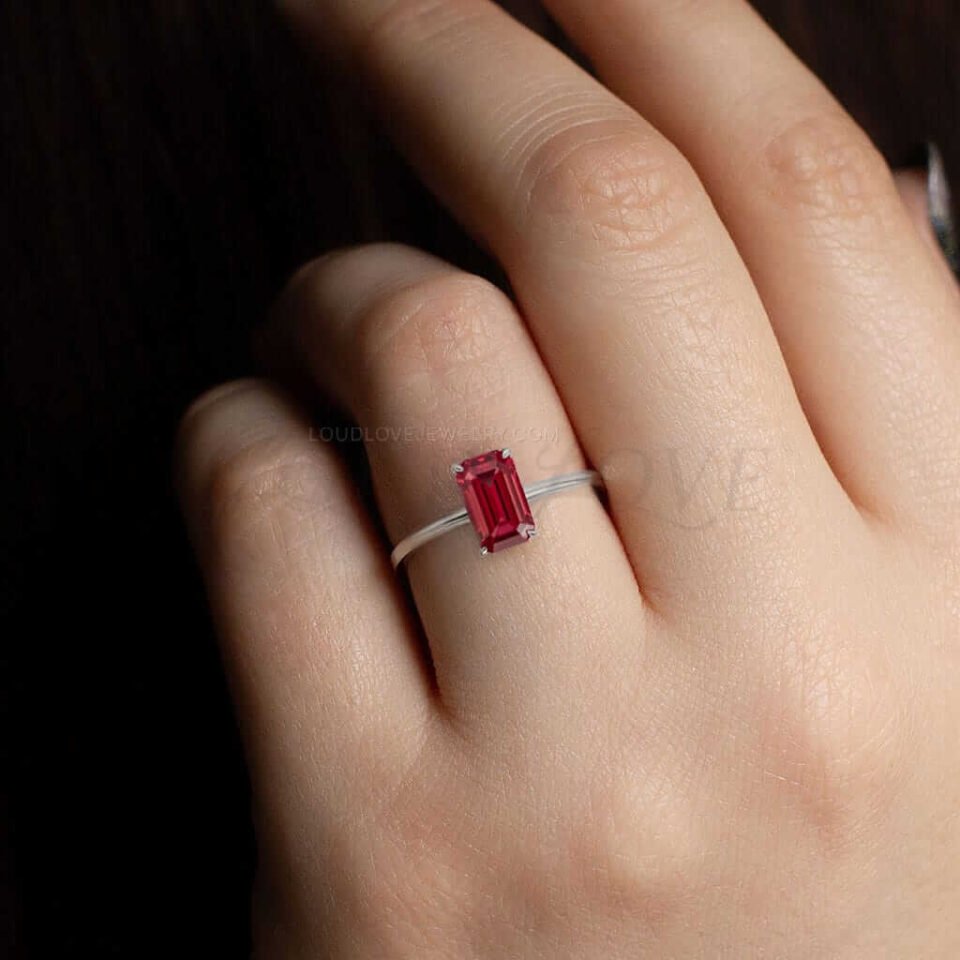 Deep red garnet in emerald cut set in white gold, worn to highlight its bold, classic design.