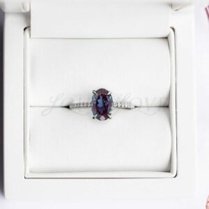 Alexandrite ring with half eternity moissanite band in soft jewelry holder.