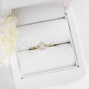 Oval moissanite engagement ring with leafy gold band presented in a stylish ring box.