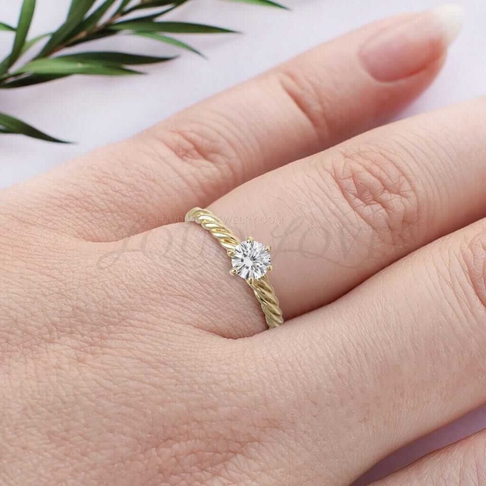 Braided yellow gold engagement ring with round solitaire stone worn as a statement piece.