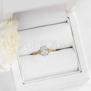 Yellow gold engagement ring with oval moissanite and tapered textured band displayed in jewelry case.