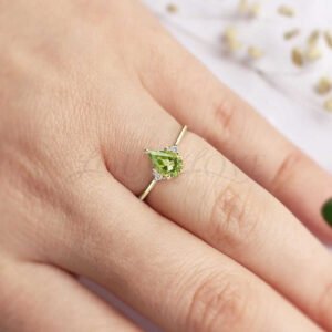 Delicate gold ring featuring pear-cut peridot and white accents, gracefully styled.