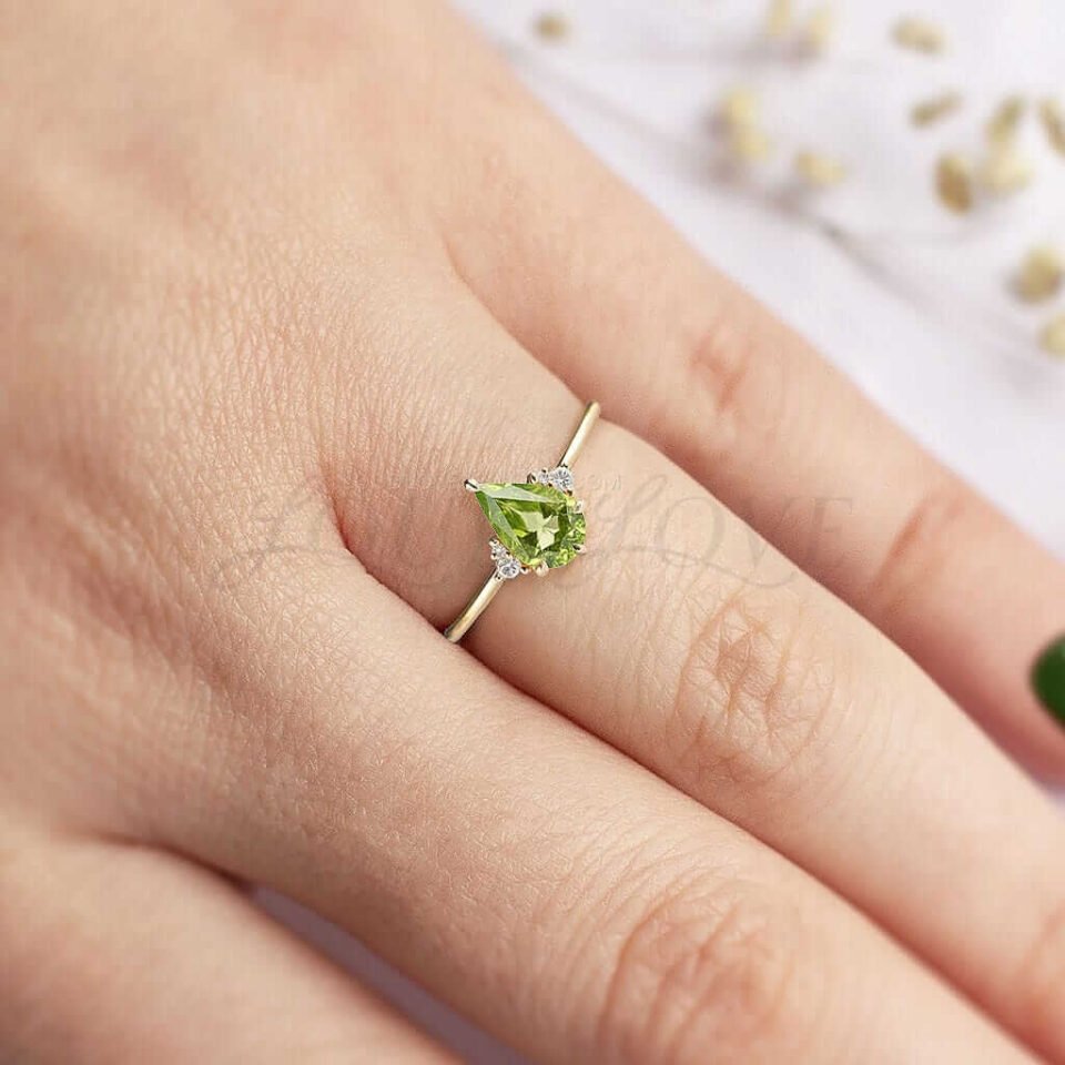 Delicate gold ring featuring pear-cut peridot and white accents, gracefully styled.